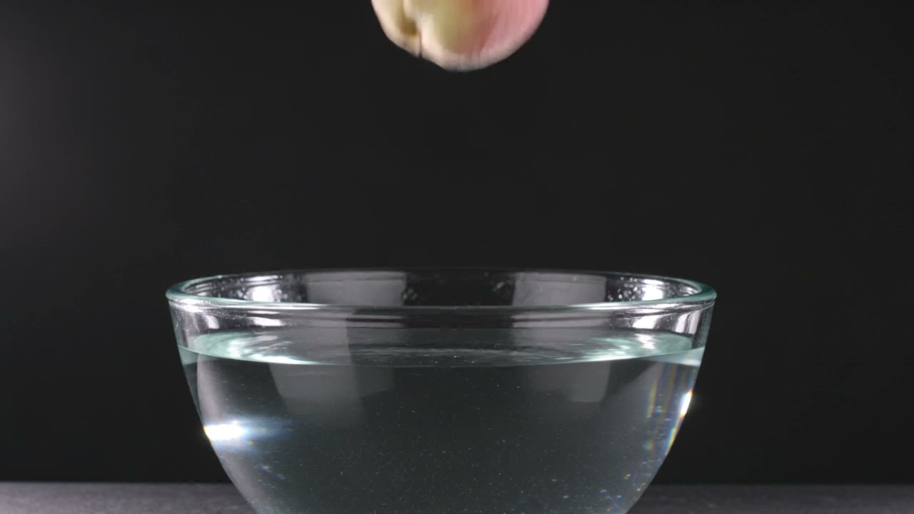 Kling V3 video: a ripe peach drops into a glass bowl of clear water in slow motion